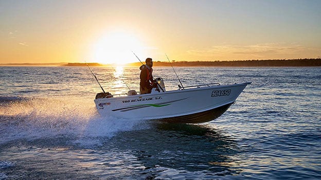 Man driving Quintrex boat at sunset