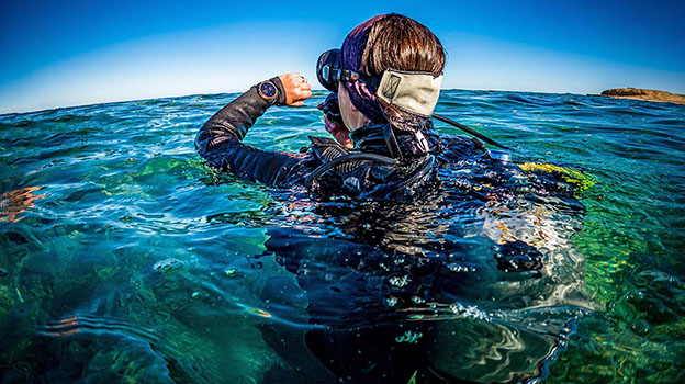 Man checking dive watch while surfacing from scuba dive
