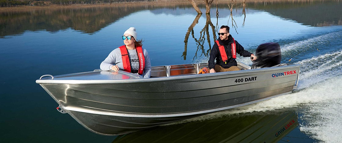 Man and woman motoring across lake in tinnie