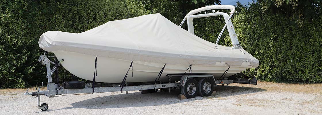 Boat on trailer with cover on parked in driveway