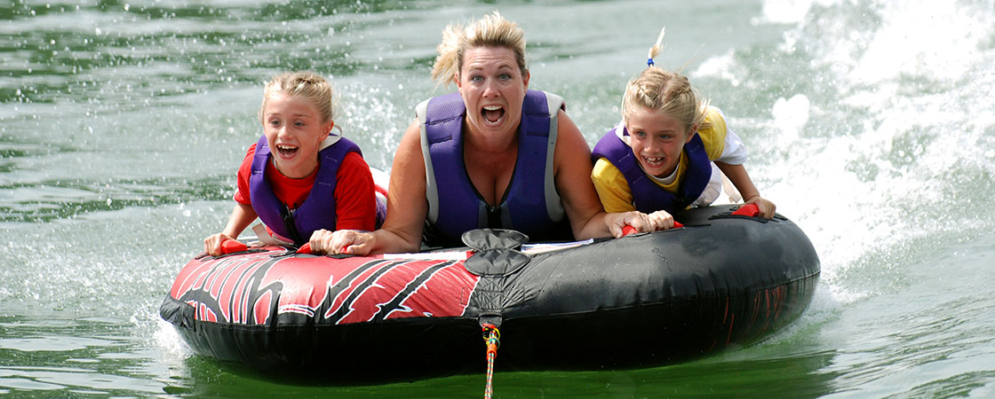 Mum and kids on tube towed behind boat
