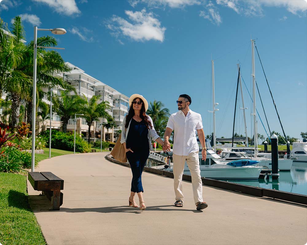 Man and woman walking hand in hand at marina